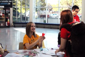 WINDSOR, ON.: Jordynne Ropat, president of the University of Windsor Mental Health Awareness group, showing a student how to make origami. (Shelbey Hernandez/The Converged Citizen)