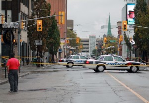 A man looks on as police cruisers are parked at the intersection of University Avenue West and Pelissier Street Oct. 19. Several stabbings in the area have left one man dead and at least three injured. (Photo by Sean Previl)