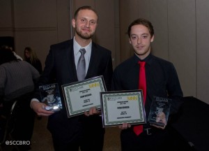 Second-year journalism student Liam Higgins (left) and first-year journalism student Ryan Brough (right) displaying their runner-up certificates and winner plaques at the Journalism Awards Night on April 3, 2014. Higgins and Brough both won the Photojournalist of the Year award for their years, Higgins for second-year and Brough for first-year. Higgins was also a runner-up for the Convergent Design award and Brough was a runner-up for the Convergence Technology award. (Photo by/Julia Chappell). 