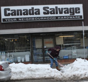 Jaimie, an employee at Canada Salvage in Windsor shovels snow in front of store. (Photo by Blake Wilson)