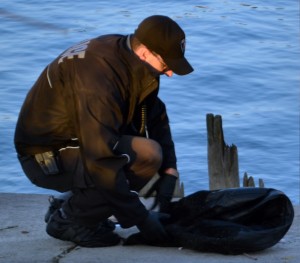Officer from Windsor Police Services examining the drenched clothes removed from a body found in the Detroit River near Lauzon and River on Nov. 11, 2015 in Windsor, ONT. (Photo By/Kenneth Bullock)