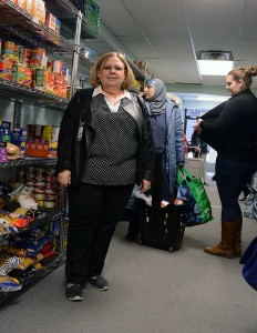 Laurie Musson is the supervisor of the Food and Clothing Bank at the Downtown Mission. Behind her a volunteer helps a local woman select food to help her family.