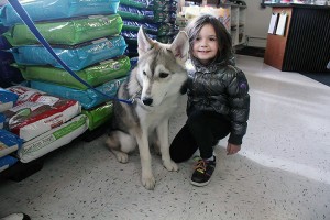 Allie (child) poses with Loki (dog) at the S.C.A.R. black tie event and bake sale.