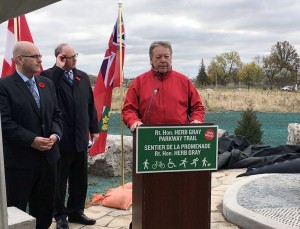 Walpole Island Chief Dan Miskokomon speaks at the podium following the opening of the Herb Gray Parkway, with Ministry of Transportation president Steven Del Duca (far left), and Windsor Mayor Drew Dilkens.